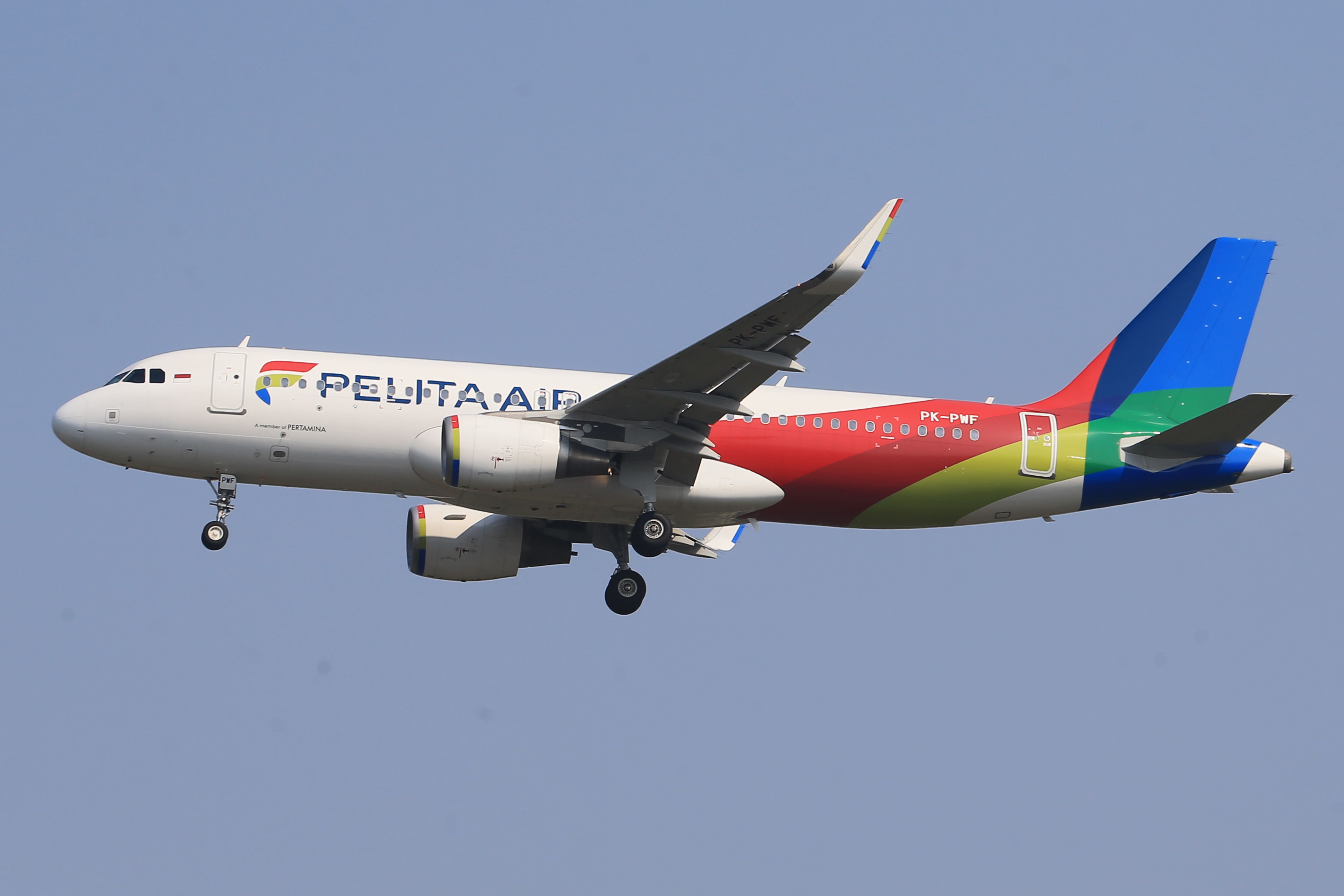 A vibrant commercial airplane flying through a clear blue sky.