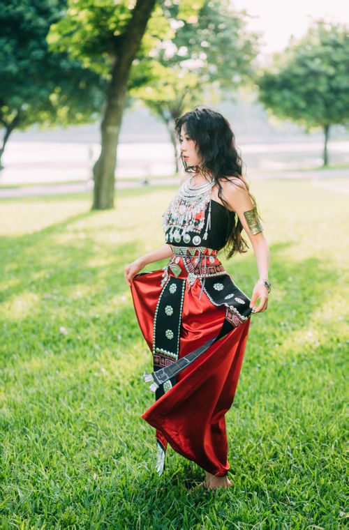 Free Elegant woman in traditional dress poses gracefully in a sunny park setting. Stock Photo