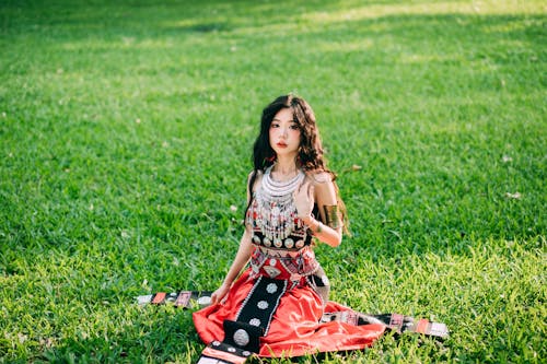 Young Woman in a Traditional Dress Sitting on the Grass 