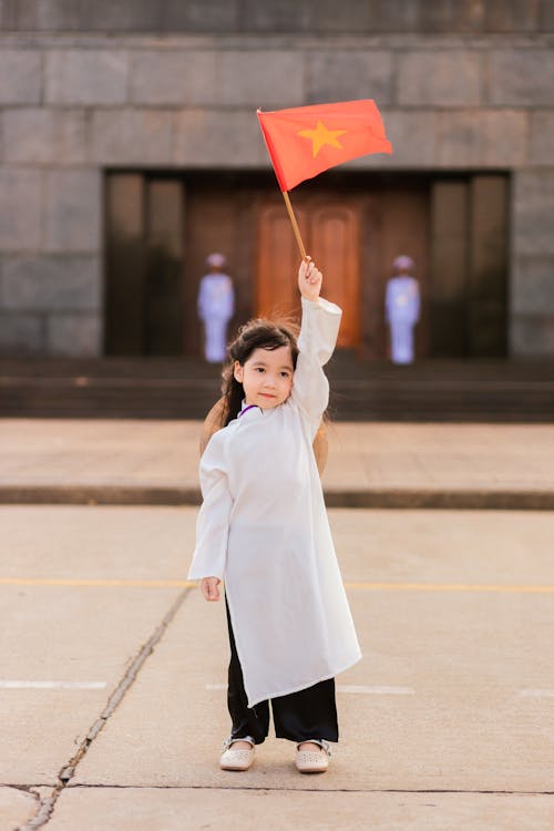 Little Girl Standing and Holding a Flag of China 