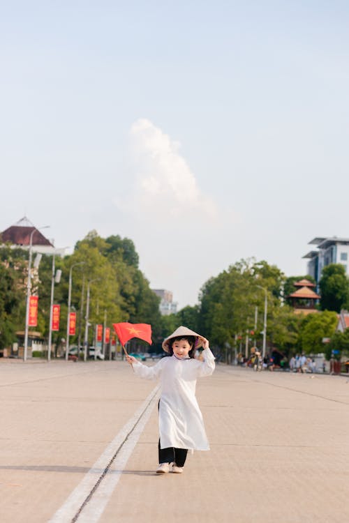 Girl Posing with a Flag of China in a Town Square 