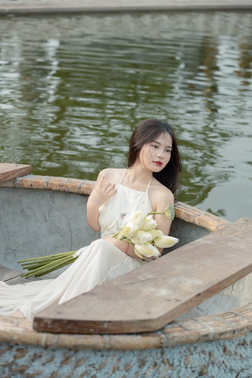Woman in White Dress and with Flowers Posing on Boat