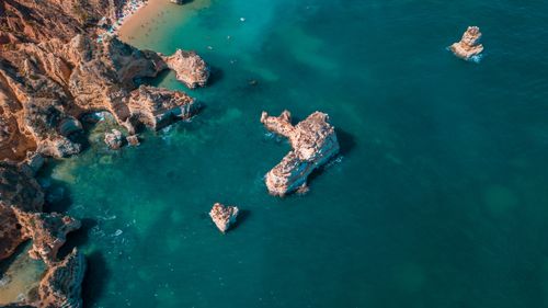 Free A breathtaking aerial view captures rocky formations and clear turquoise waters along a sunny coastline. Stock Photo