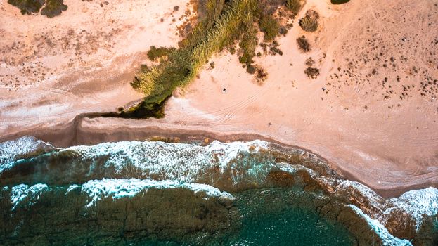 Stunning aerial view of a sandy beach with ocean waves crashing onto the shore.