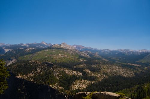 Free Breathtaking view of a mountain range with lush forests under a clear blue sky. Stock Photo