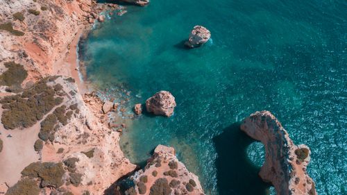 Free Breathtaking aerial photograph capturing rocky cliffs and turquoise sea in a serene coastal setting. Stock Photo