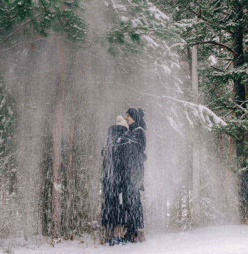 Couple Standing under Snow Falling from the Trees 