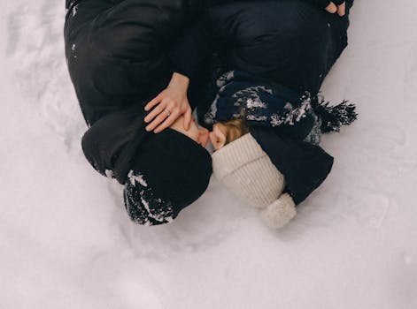 Young couple embracing intimately in the snow, showcasing affection and warmth amidst the winter chill.