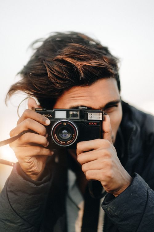 Free A young man capturing moments with a vintage Yashica camera outdoors. Stock Photo