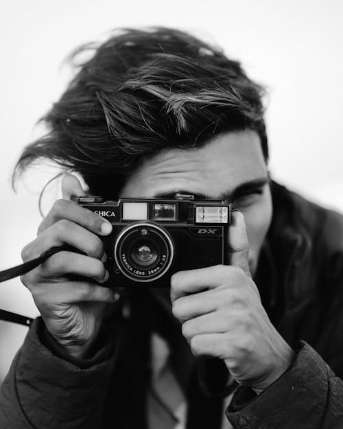 Black and White Photo of Man with Analog Camera