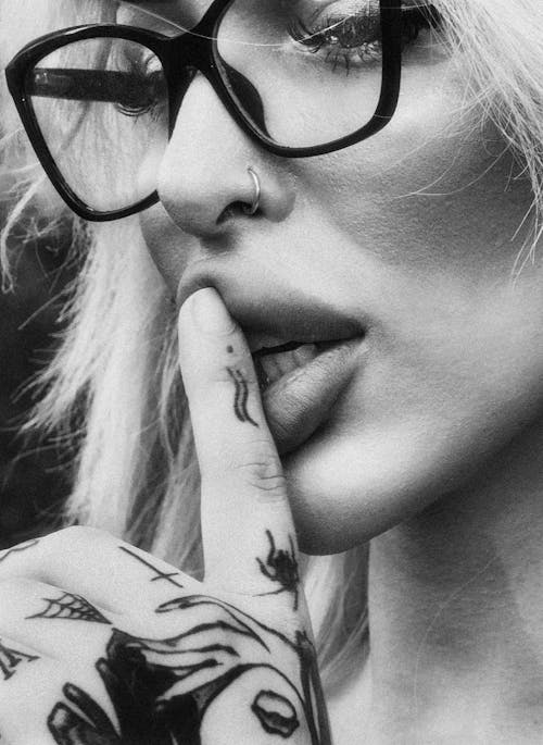 Woman with Tattooed Hands Holding Index Finger on Lips