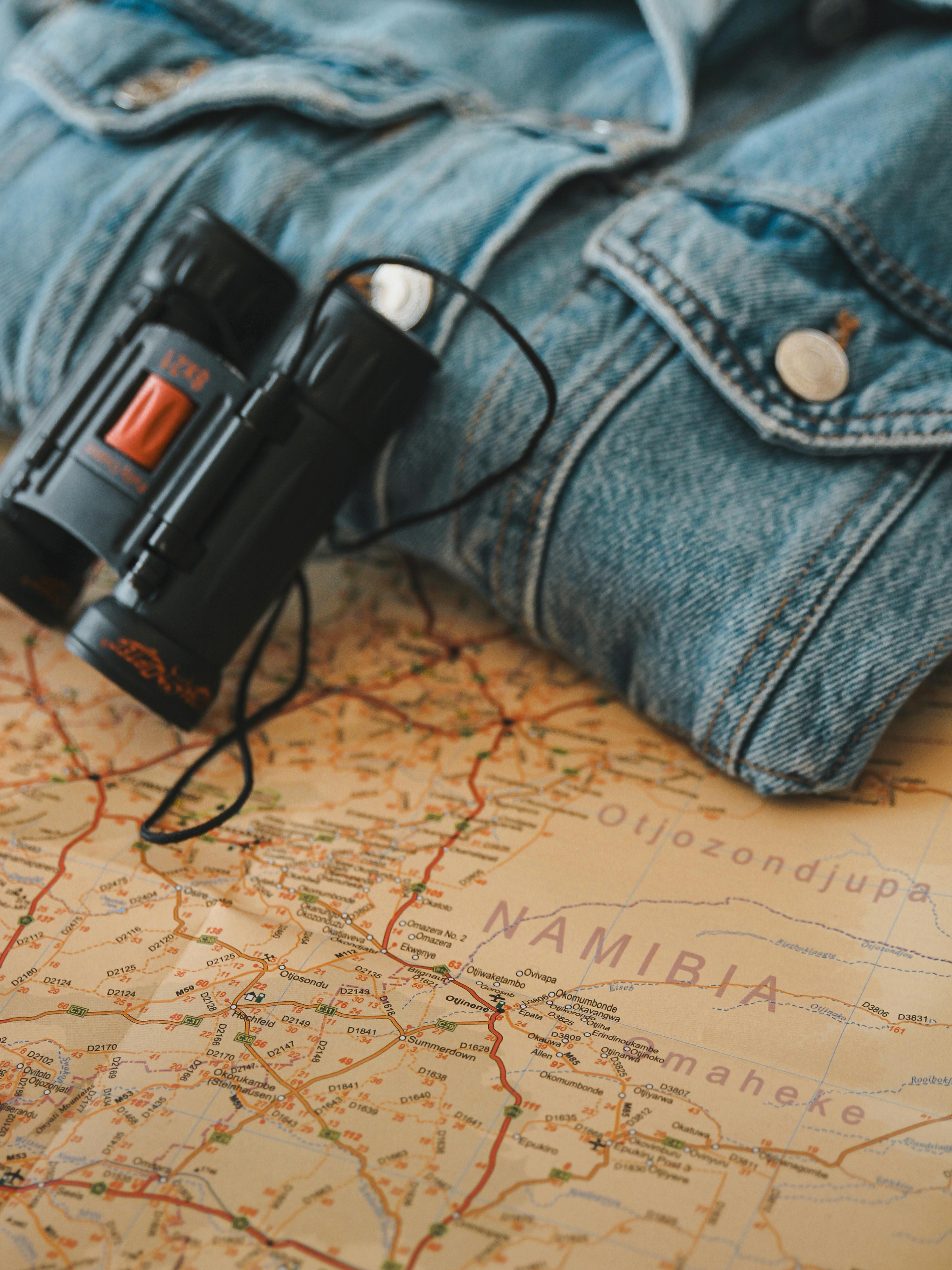 Binoculars and denim jacket on map of Namibia reflect travel spirit.