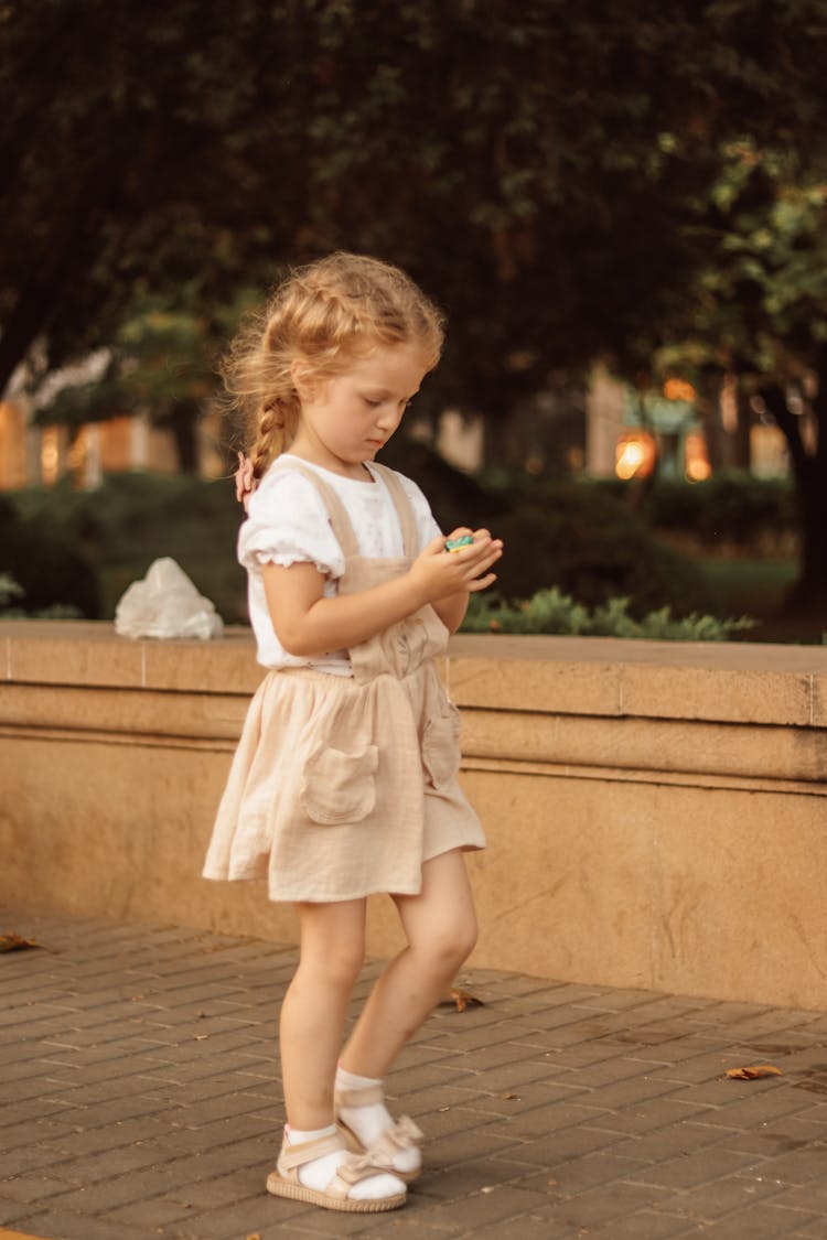 Girl Walking On Paving And Looking On Toy