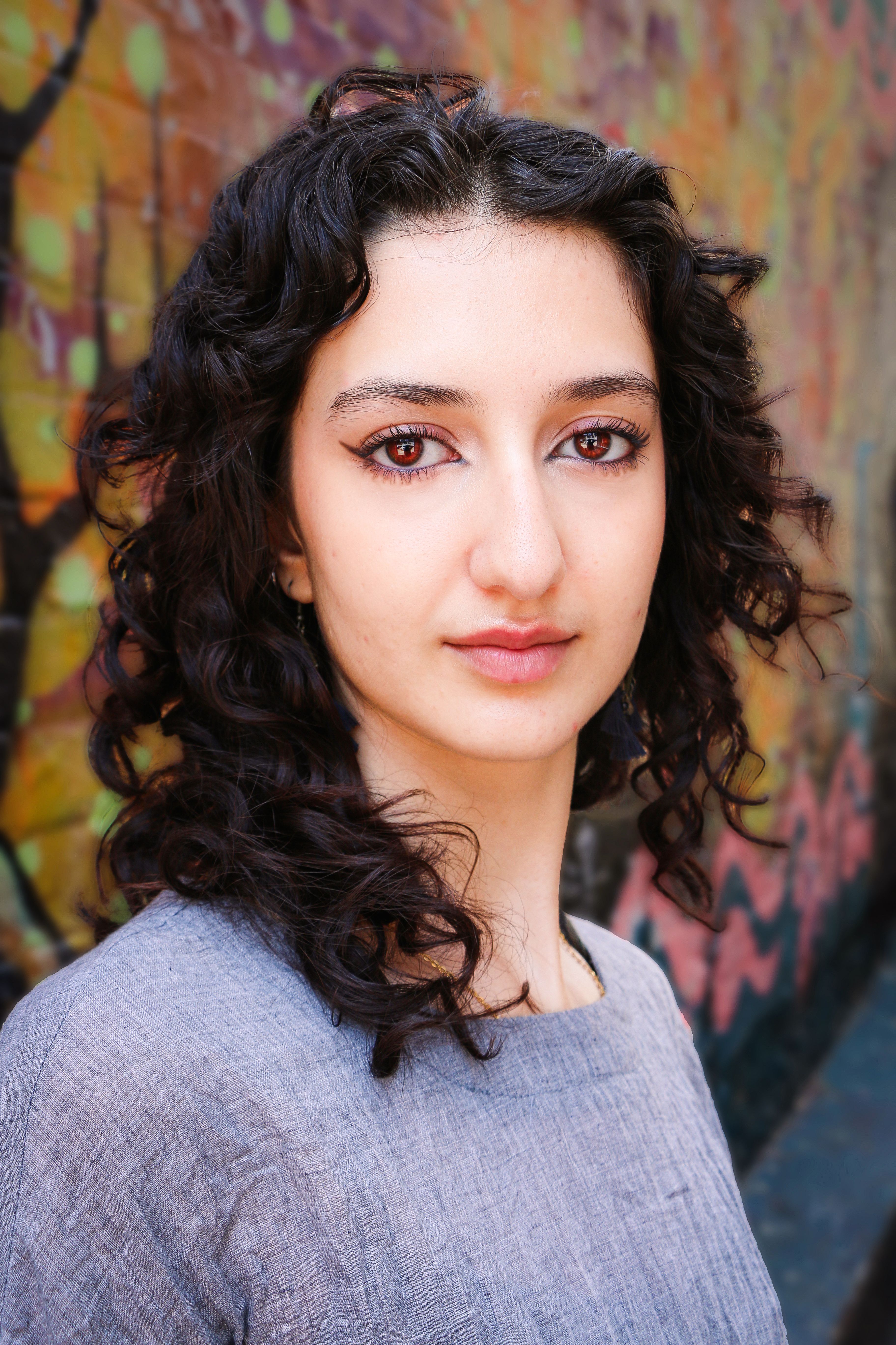 Striking portrait of a woman with curly hair against colorful graffiti in Brighton and Hove.