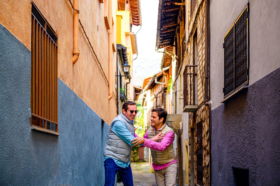 Dos amigos alegres riendo y abrazándose en un vibrante callejón de la ciudad en un día soleado.