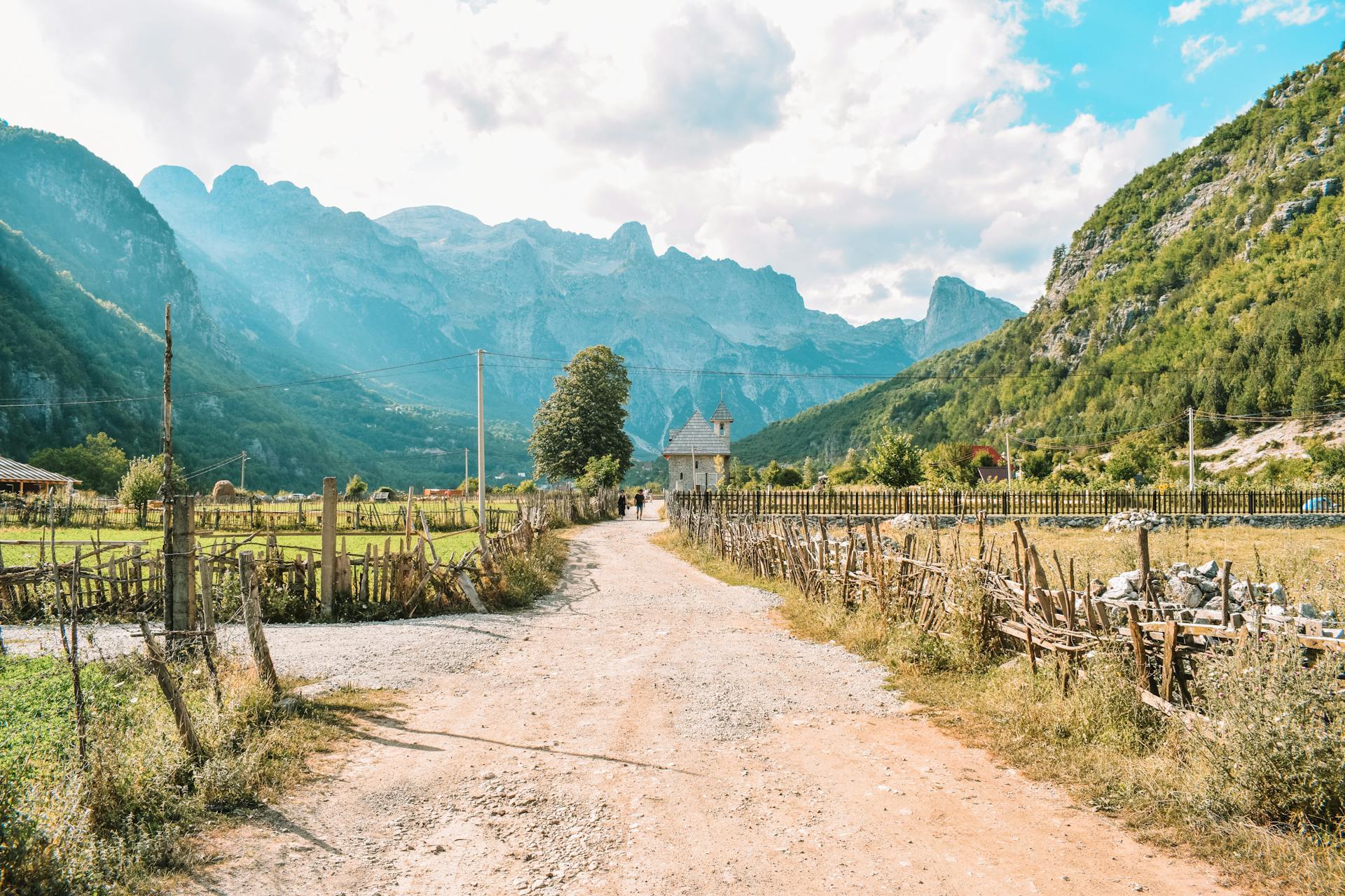 Explore the tranquility of an Albanian country road with stunning mountain views.