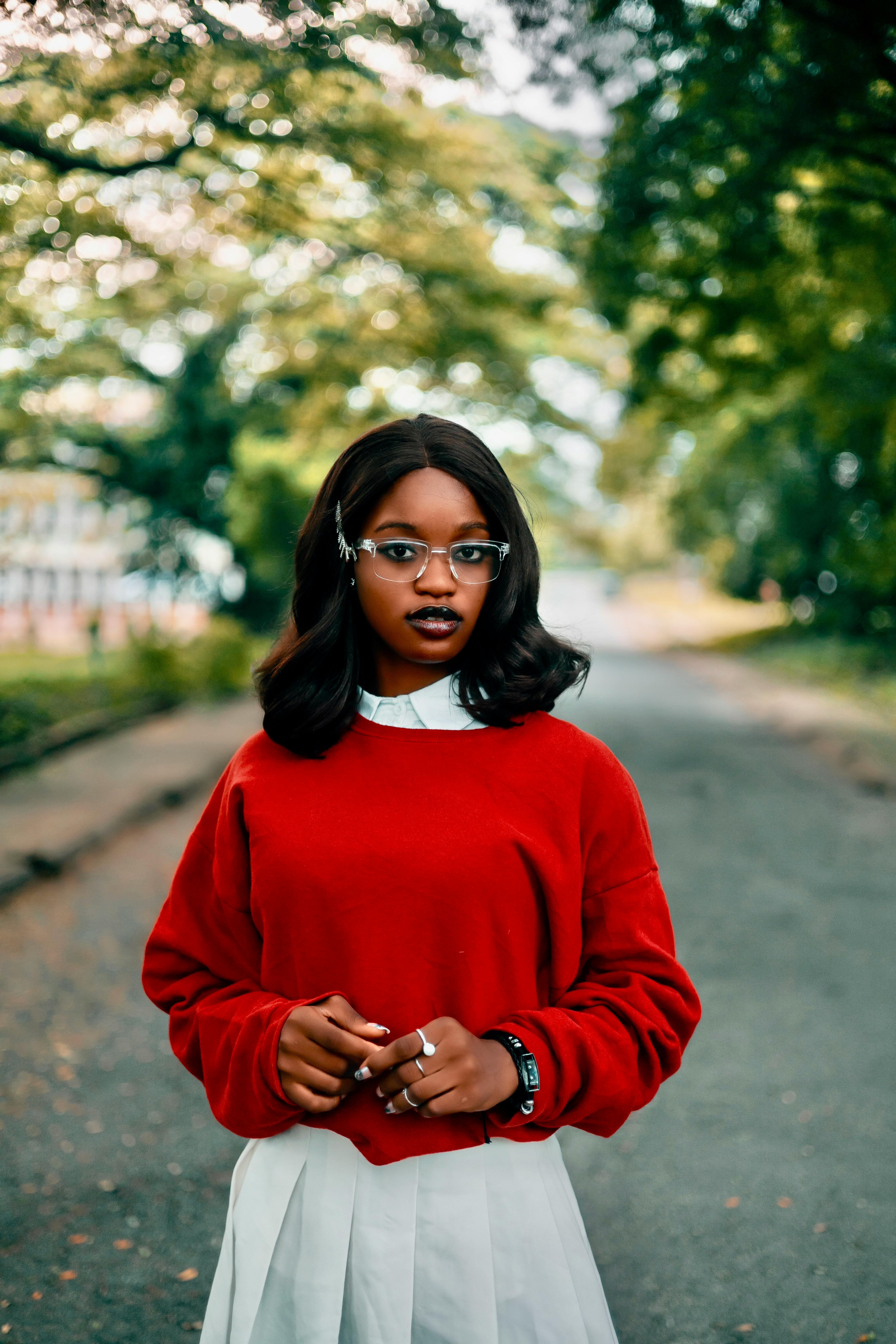 Stylish young woman in a red sweater walking outdoors in Ibadan, Nigeria.