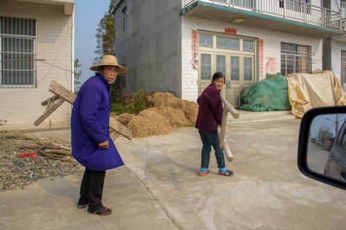 Free Elderly Asian couple engaged in tasks outside a rural village home, embodying traditional rural life. Stock Photo