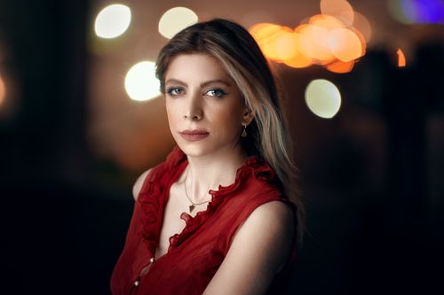 Free Captivating portrait of a blonde woman in a red dress with bokeh lights background. Stock Photo
