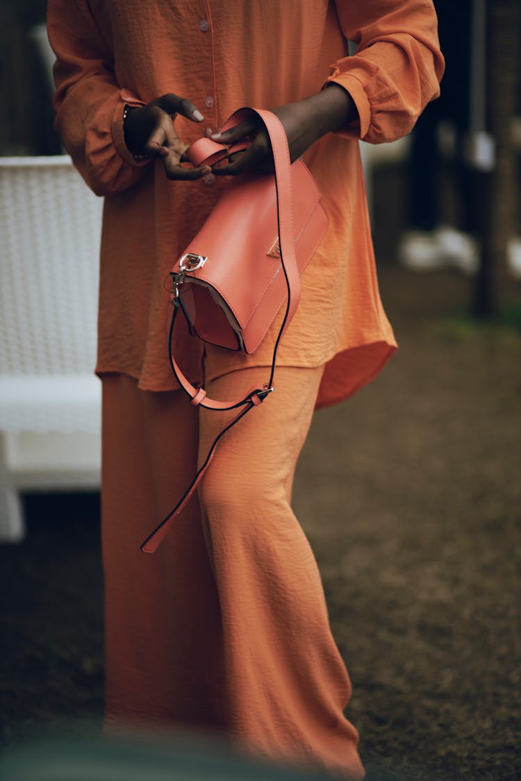 Woman In Orange Shirt At Pants Holding An Orange Purse