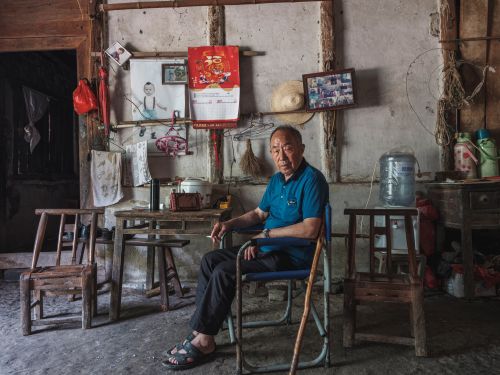Free Senior man seated in a rustic workshop surrounded by tools and decor. Stock Photo