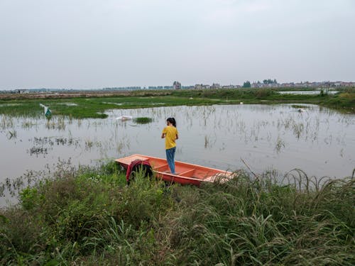 Person Standing on Boat on Swamp in Countryside