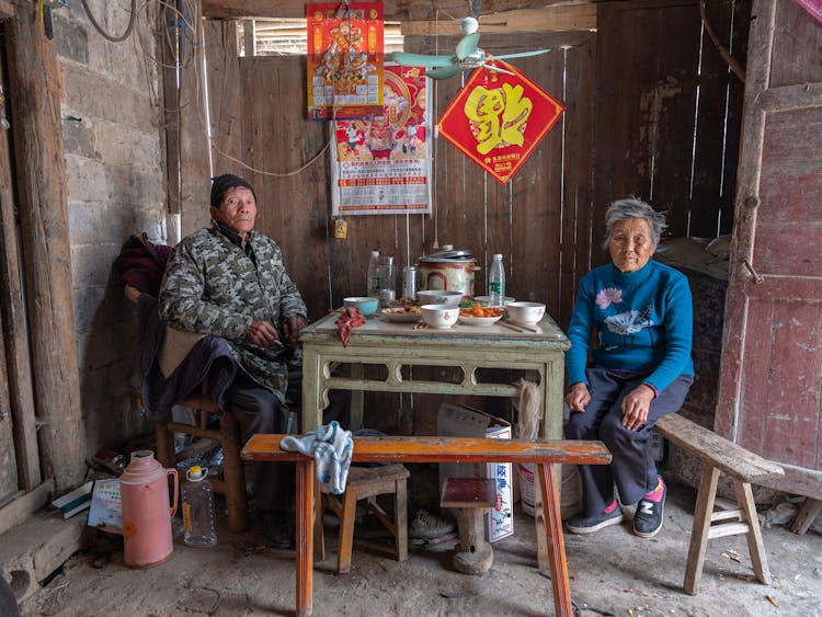 Woman And Man Sitting By Table In House