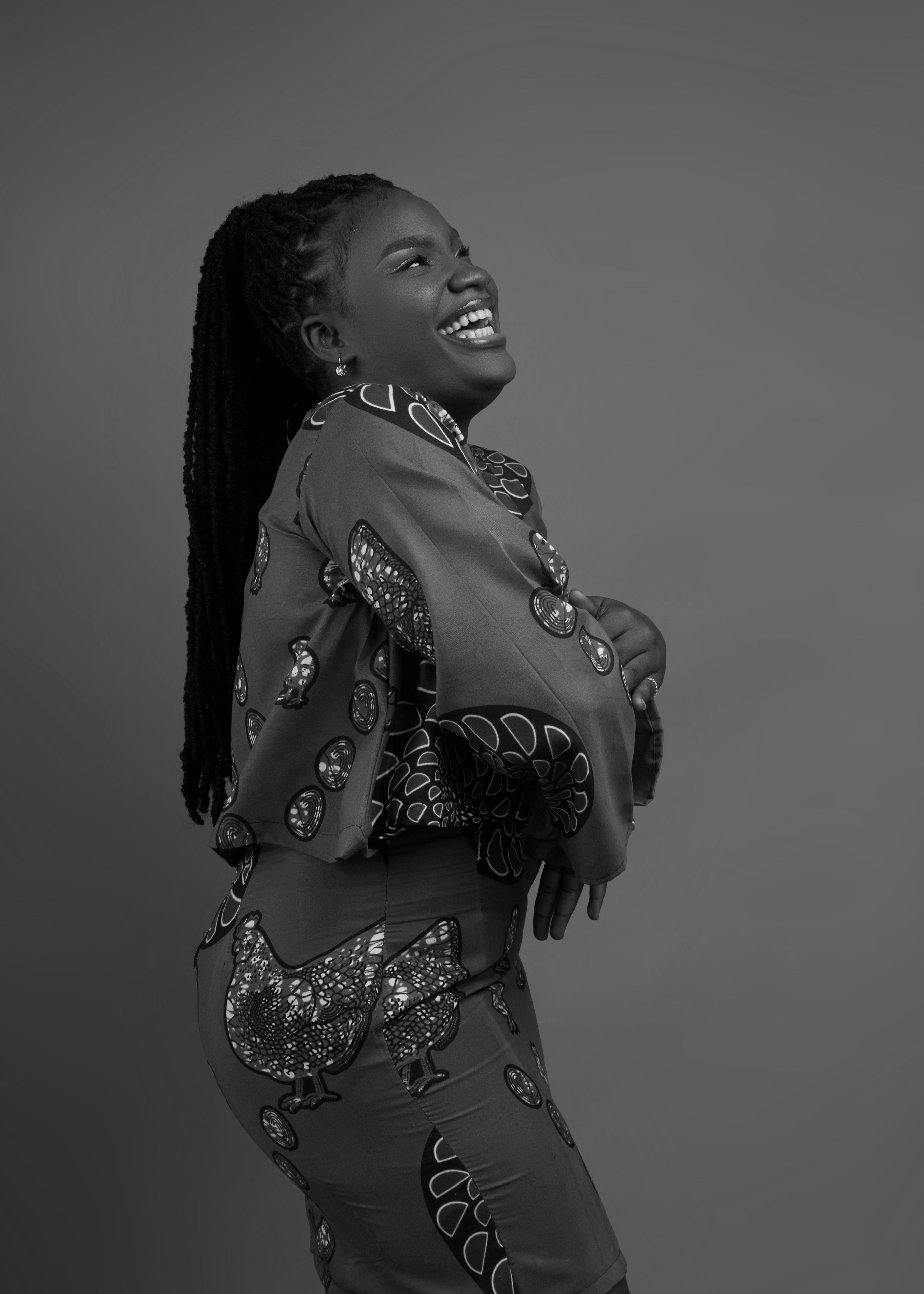 Stylish black woman in patterned clothing, captured in a joyful black and white portrait.