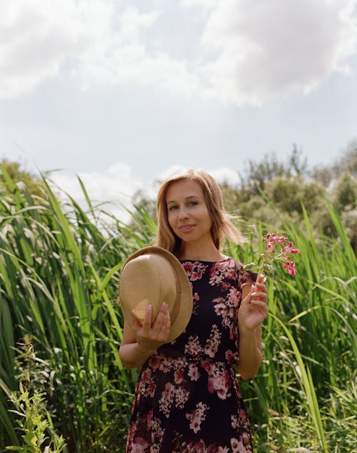 Woman in Hat and with Flowers on Meadow