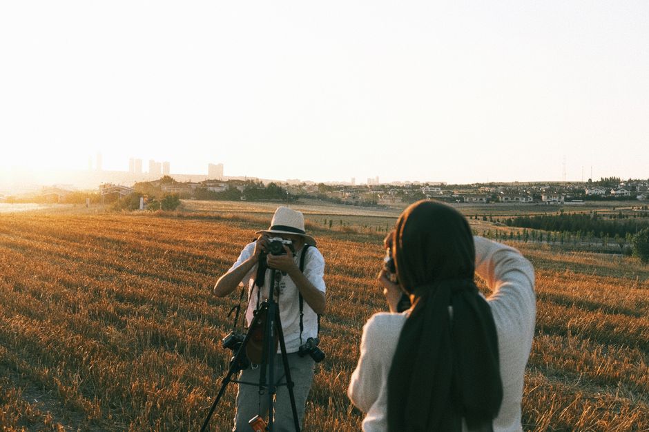 Hora dourada de verão com luz rasante sobre campo aberto e silhueta de fotógrafo