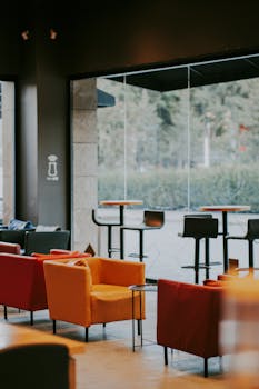 Modern café with vibrant armchairs and glass windows creating a bright atmosphere.