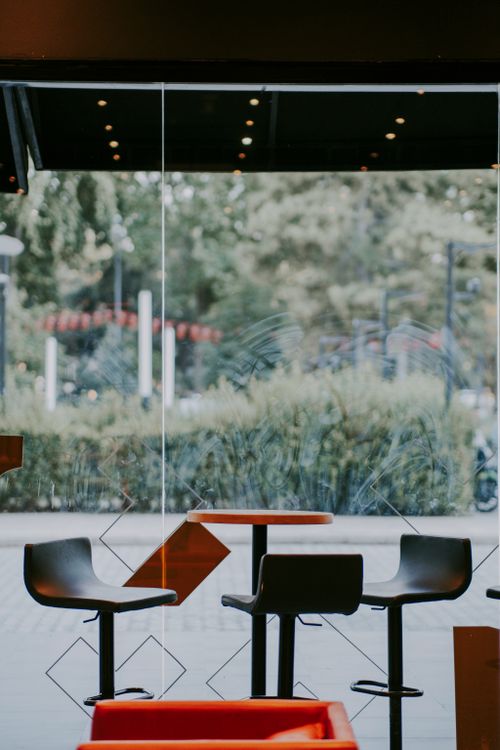 Free Interior of a modern café with high chairs and a glass window providing an outdoor view. Stock Photo