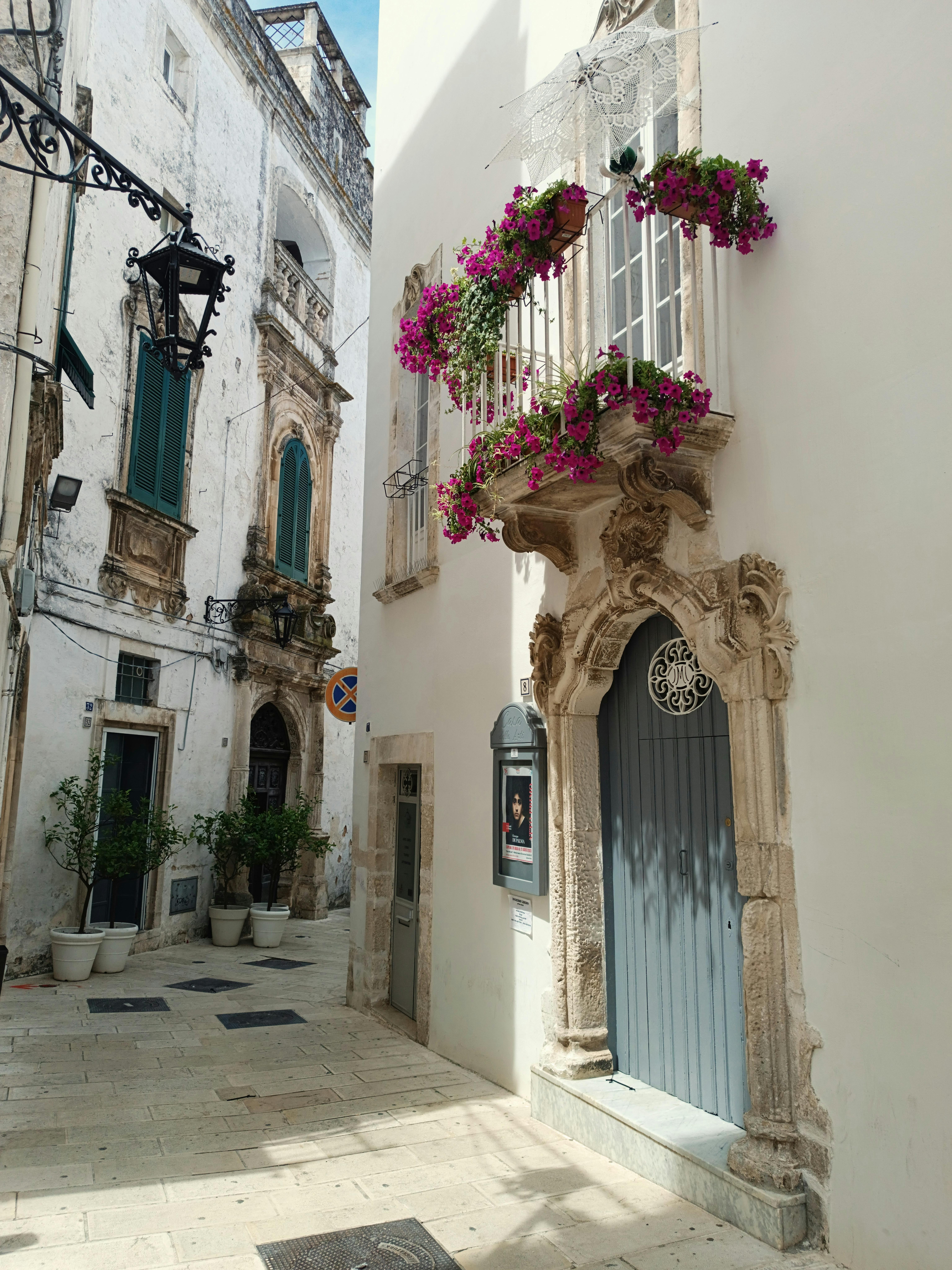 Beautiful alleyway in Martina Franca, Italy with historic buildings and vibrant flowers.