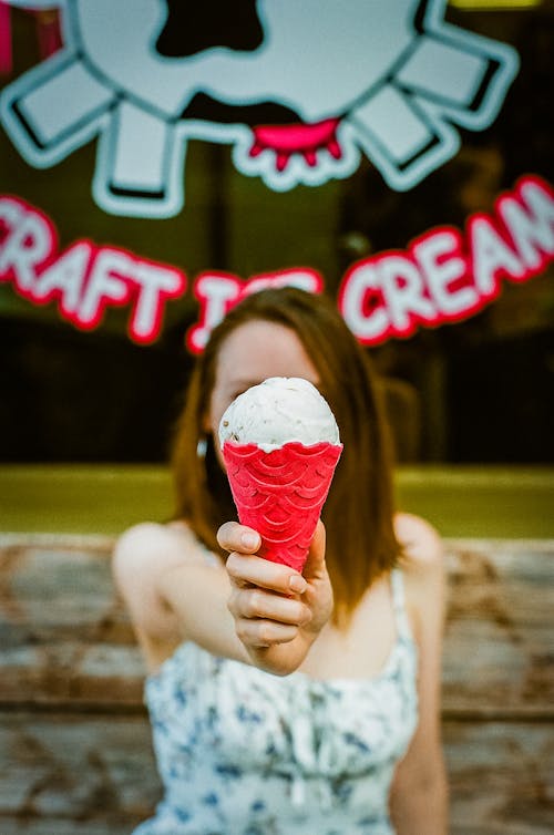 White Ice Cream in Red Cone in Hand of Brunette Woman