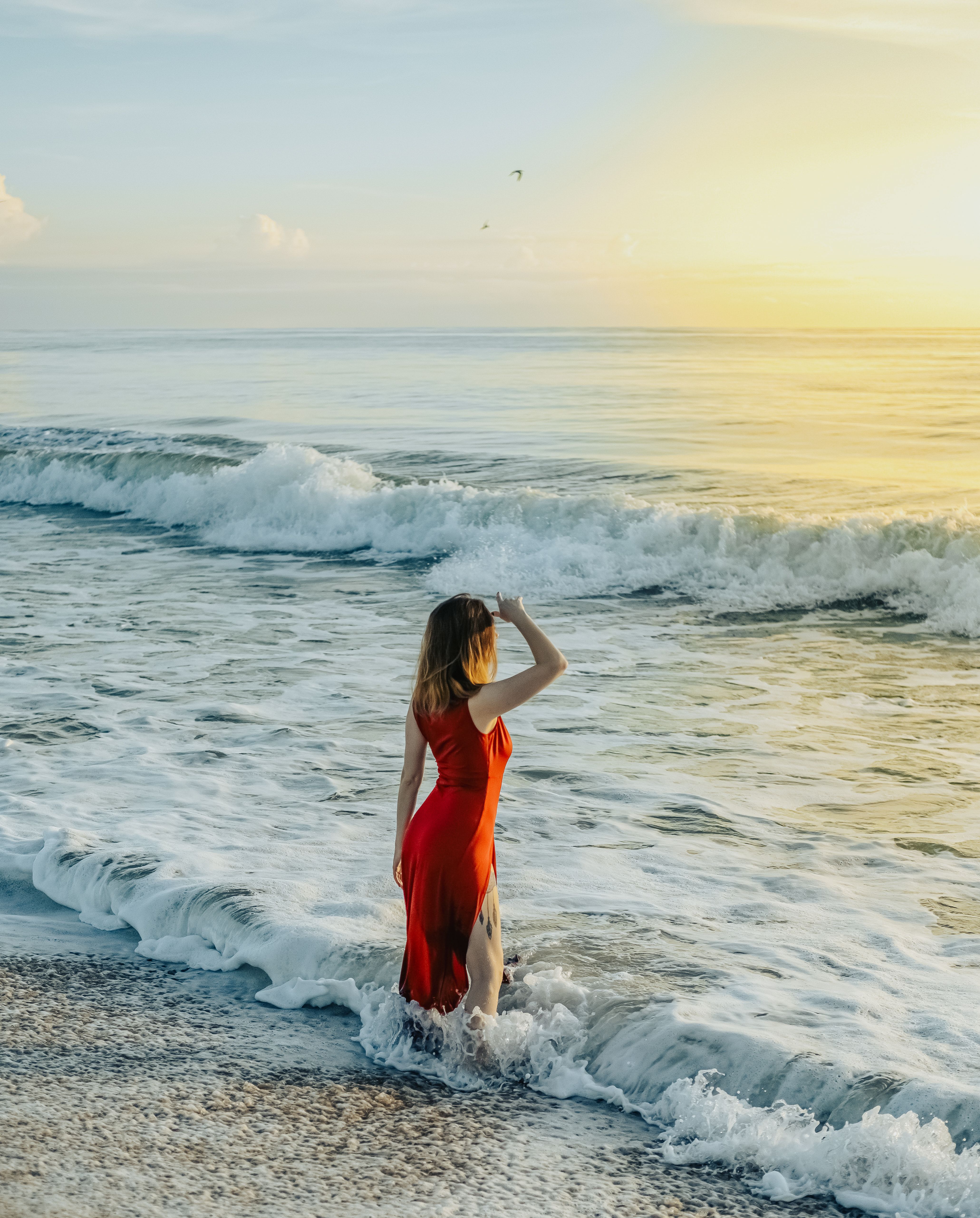 A Woman in a Red Dress Standing on the Shore Free Stock Photo A Woman in a Red Dress Standing on the Shore Free Stock Photo