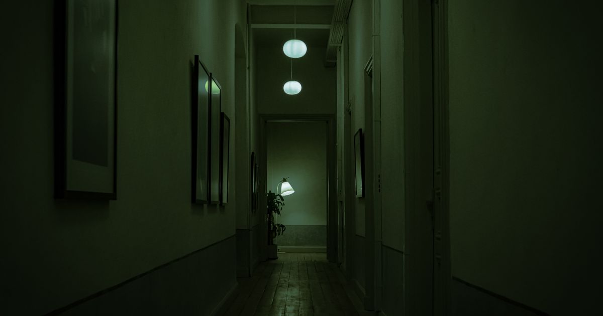 Explore the moody atmosphere of a narrow corridor with green lighting and hanging lamps.