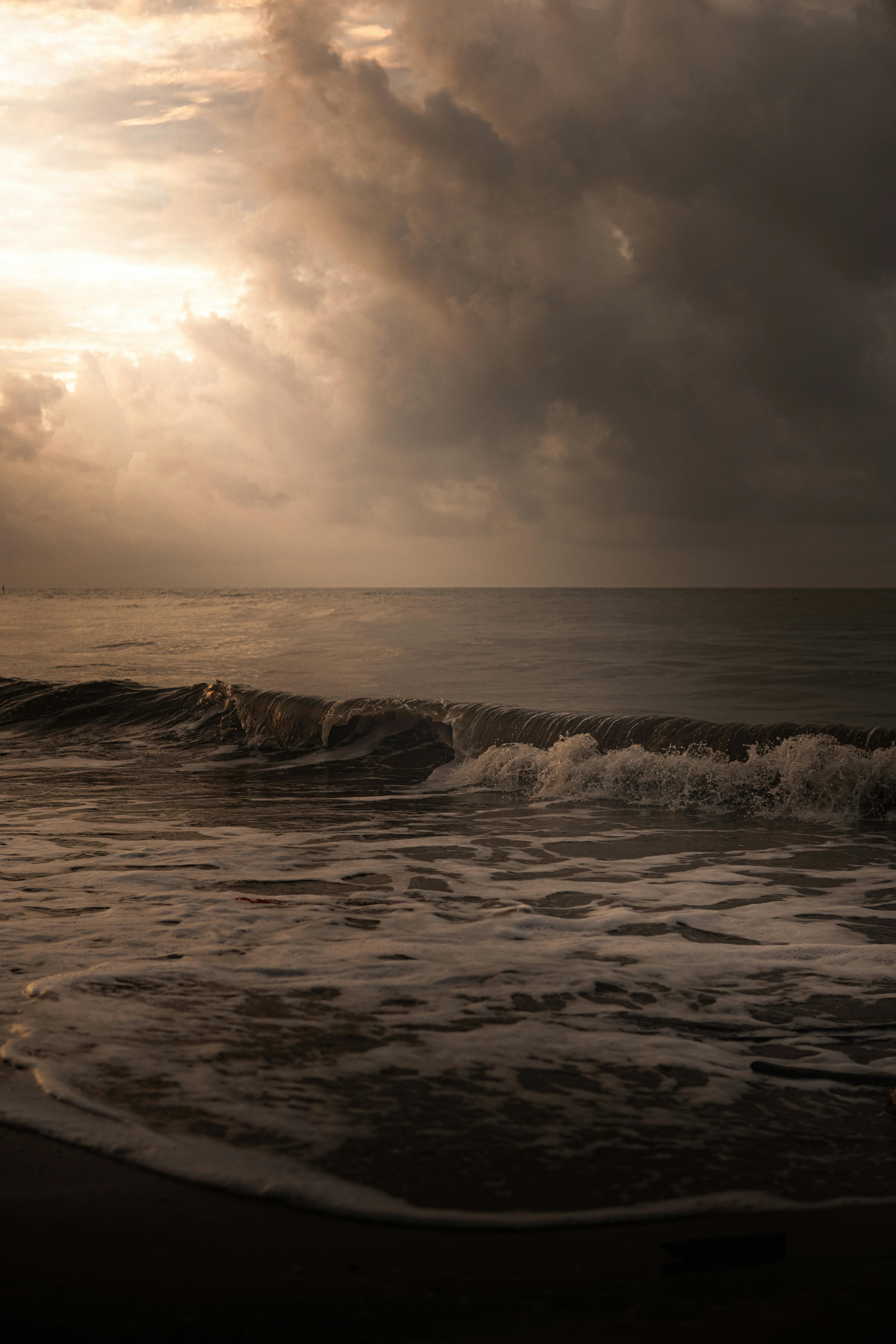 Captivating image of ocean waves and dramatic clouds at sunset, ideal for beach lovers and scenic views.