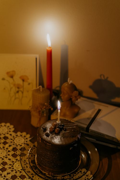 Free Warm candlelit setup with a chocolate cake, sculpture, and vintage decor in soft focus. Stock Photo