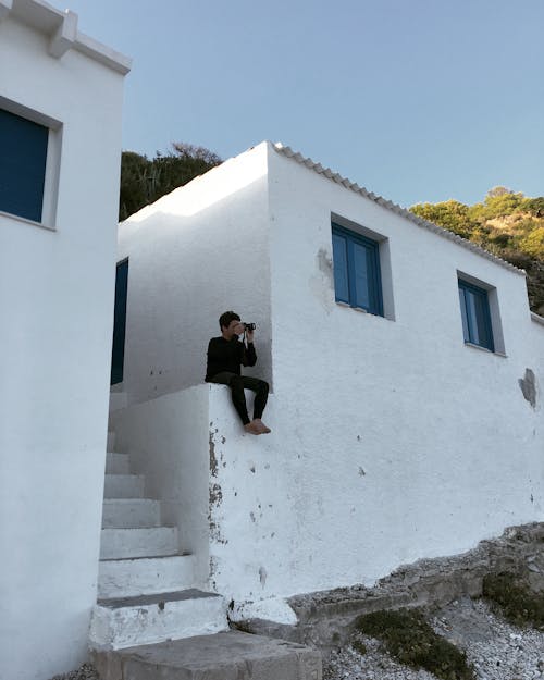 Man Sitting Near White Building