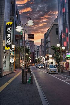 A bustling city street scene with vibrant lights and a stunning sunset sky.