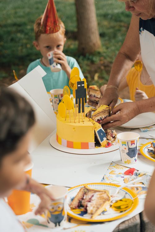 Free Children enjoying a birthday party with a Minions themed cake and decorations outdoors. Stock Photo