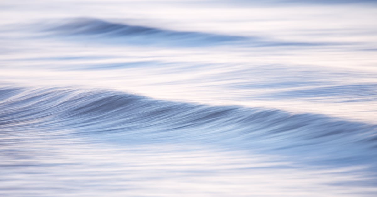 Peaceful image of soft waves in the ocean at sunset with gentle blue tones.