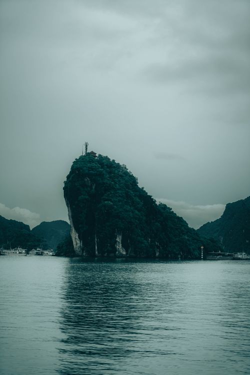 Free Stunning view of a limestone karst formation in Ha Long Bay, Vietnam with calm water and distant boats. Stock Photo