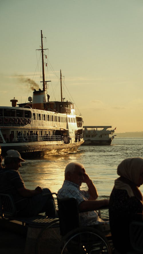 Vessel behind People Sitting on Shore