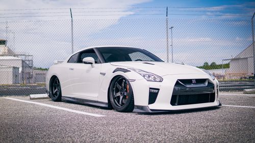Free A customized white Nissan GT-R parked in an urban parking lot, emphasizing its sporty design. Stock Photo
