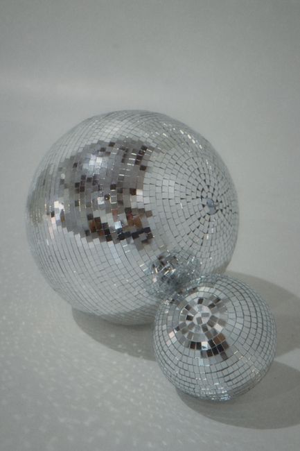 Close-up image of two glittery disco balls on a white background, perfect for party themes.