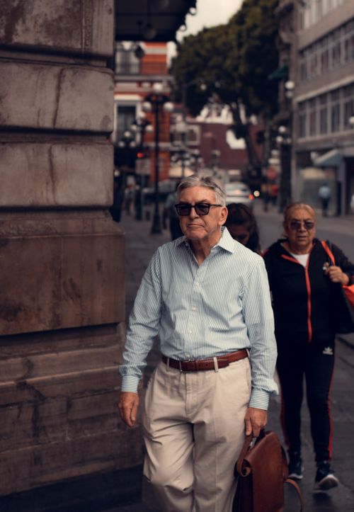Free Senior man strolling on the streets of Puebla de Zaragoza, Mexico, showcasing local architecture. Stock Photo