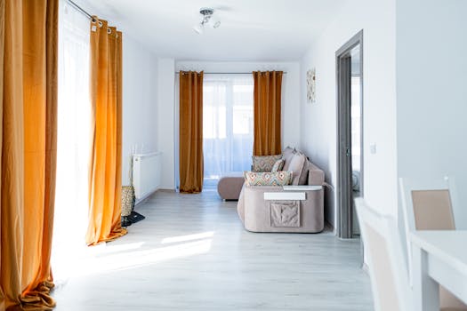 Contemporary living room featuring orange curtains and stylish beige couch. Bright and inviting interior design.