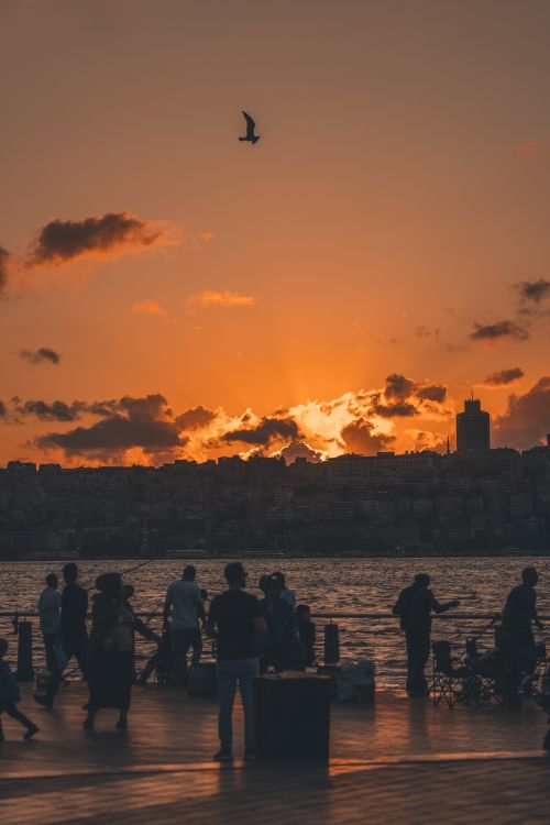 Free Silhouettes of people on an Istanbul pier during a vibrant sunset. Perfect travel shot. Stock Photo