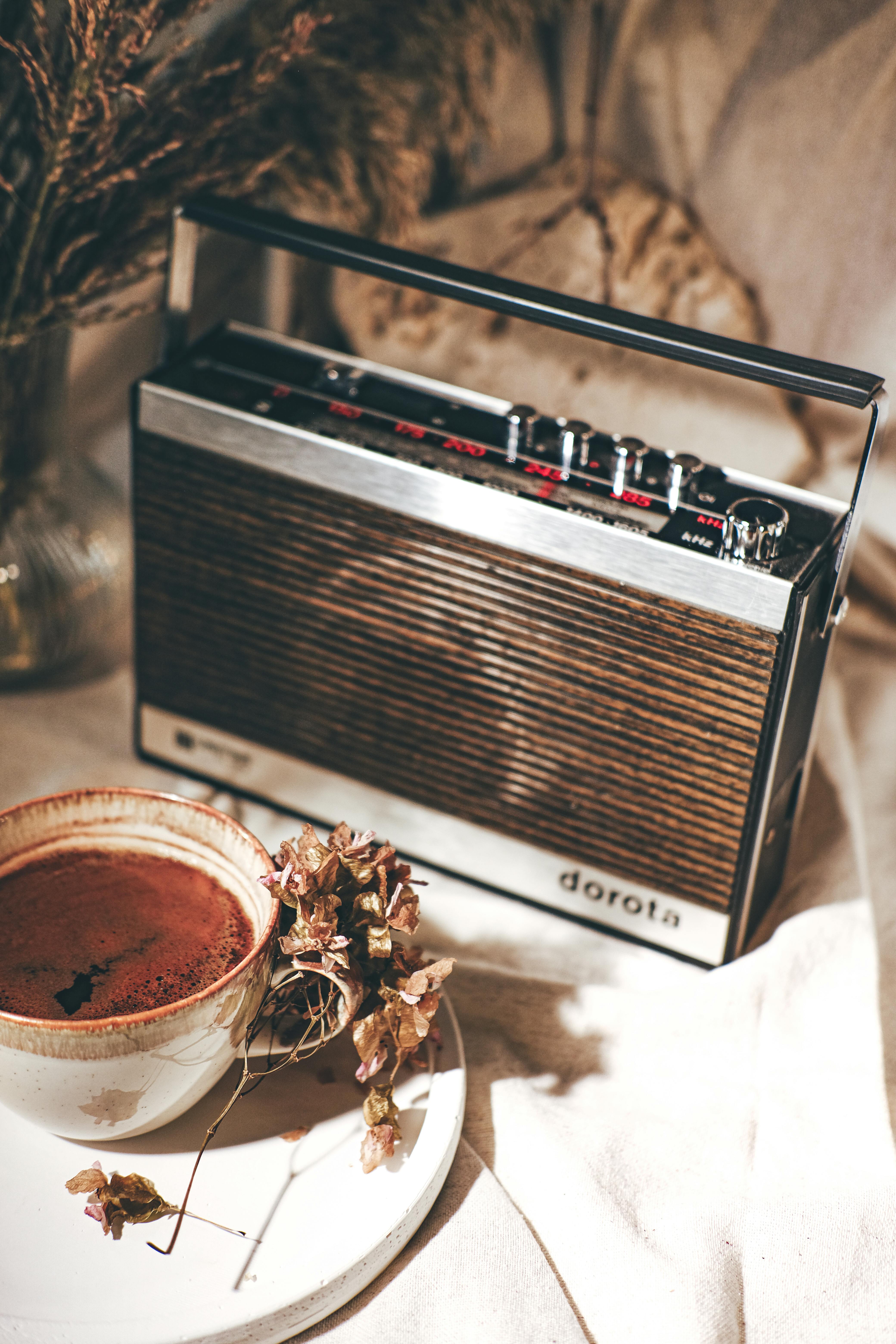 Retro still life with vintage radio, coffee cup, and dried flowers.